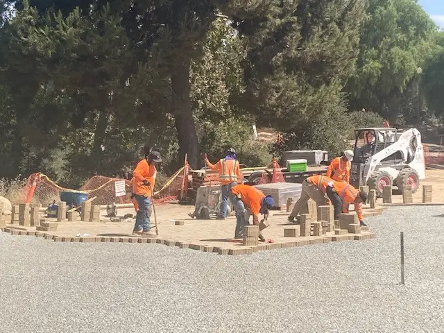 Workers constructing brick pavement at a construction site.
